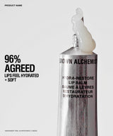 A silver tube of Brown Alchemist Hydra-Restore Lip Balm with a white balm smear at the tip, shown on a light gray background with promotional text on the left.