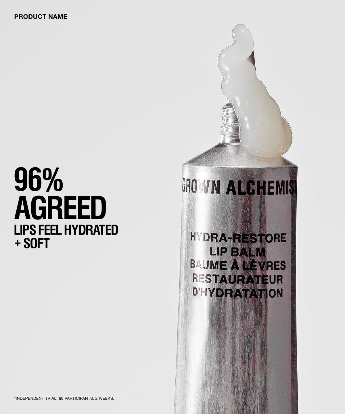 A silver tube of Brown Alchemist Hydra-Restore Lip Balm with a white balm smear at the tip, shown on a light gray background with promotional text on the left.
