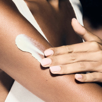 Close-up of a hand applying cream to a shoulder