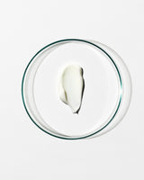 Glass bowl with a small amount of white cream on a white background