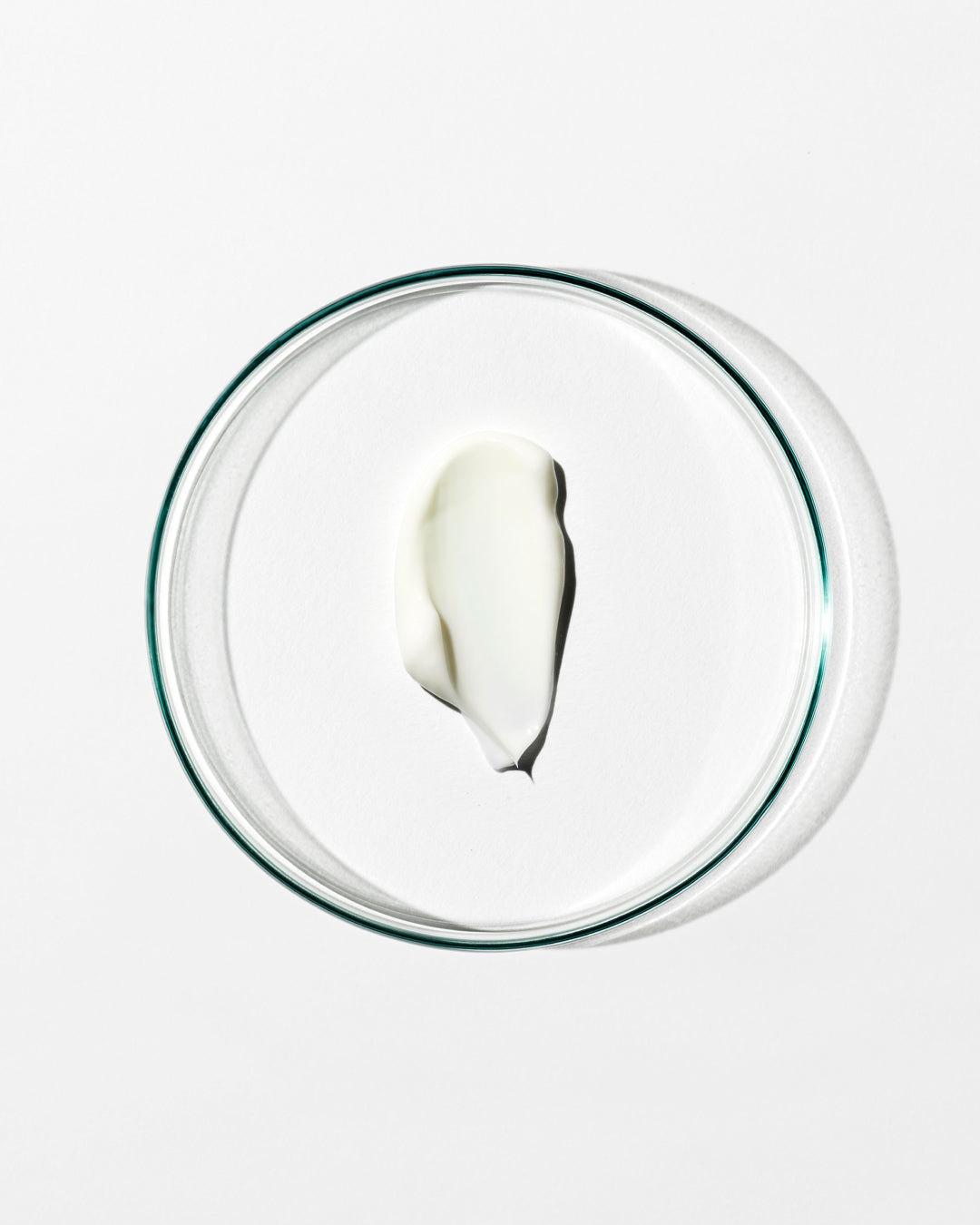 Glass bowl with a small amount of white cream on a white background