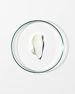 Glass bowl with a small amount of white cream on a white background