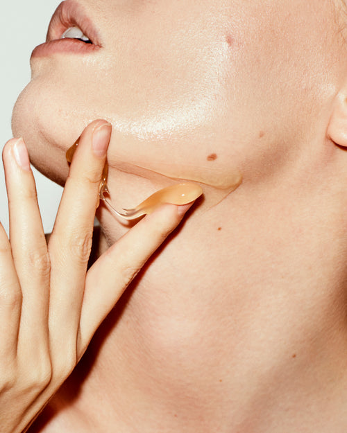 Close-up of a hand applying a skincare product to the neck.