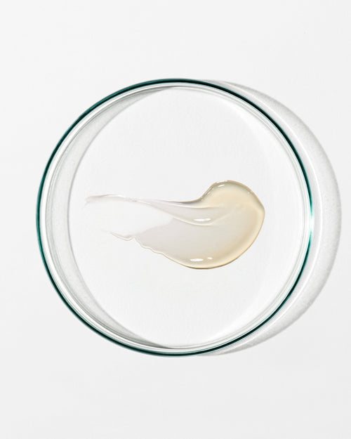 Glass bowl with a small amount of white cream on a white background