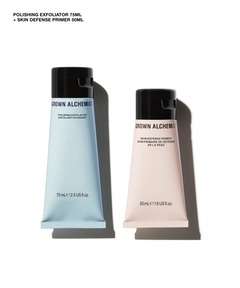 Two cosmetic tubes from BROWN ALCHEMIST on a white background, one light blue 75mL exfoliator and one pale pink 50mL skin defense primer, with black caps.