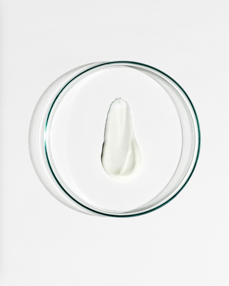 Clear dish with a dollop of white cream on a white background