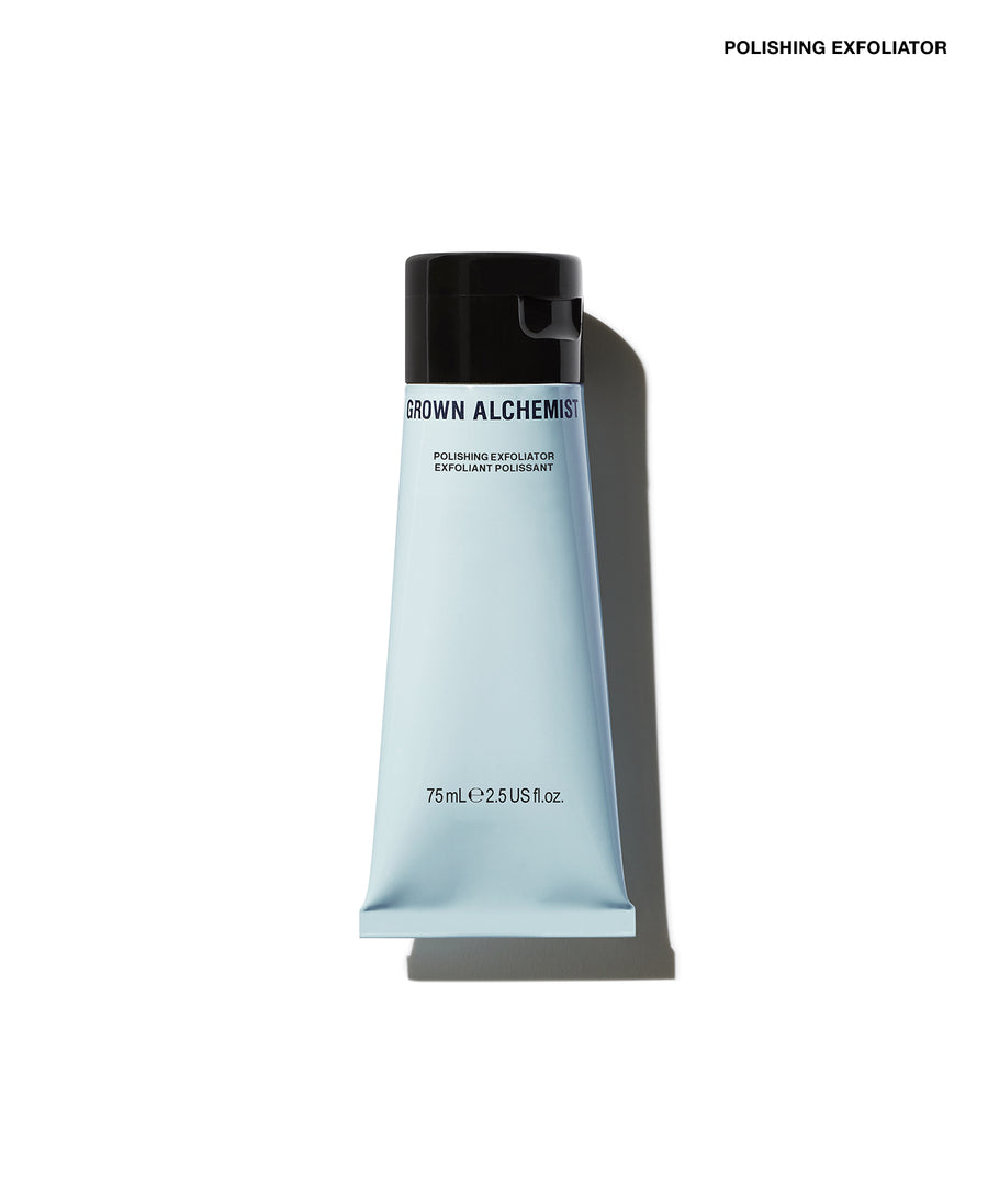 A squeeze tube of Grown Alchemist Polishing Exfoliator on a clean white background with a soft shadow. The tube is a very pale icy blue with a black cap, and the brand name 'GROWN ALCHEMIST' is printed in black on the front.