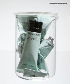 A clear glass jar filled with multiple tubes of GROWN ALCHEMIST regenerating gel mask in a pale sage green color, set against a clean white background.