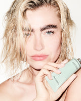Person holding a tube of Regenerating Gel Mask with a neutral background