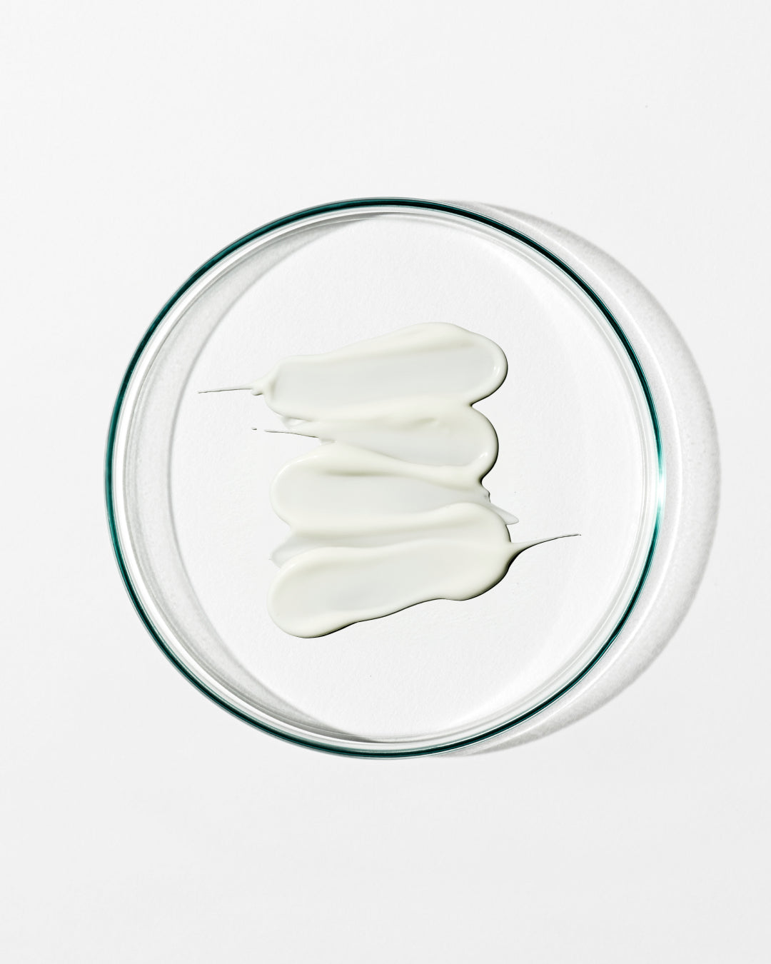 White cream in a clear glass bowl on a white background