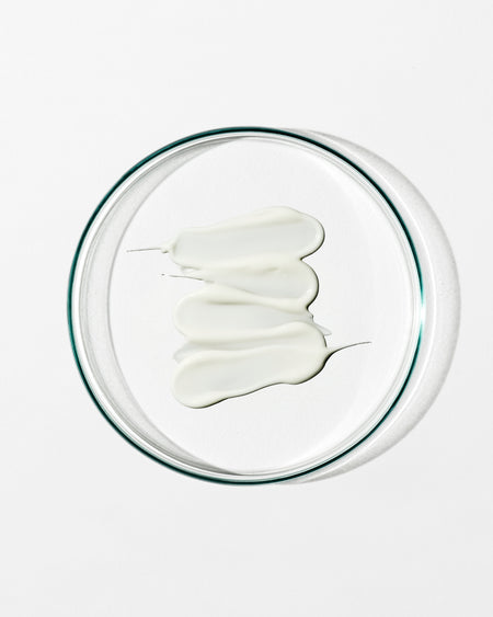 White cream in a clear glass bowl on a white background