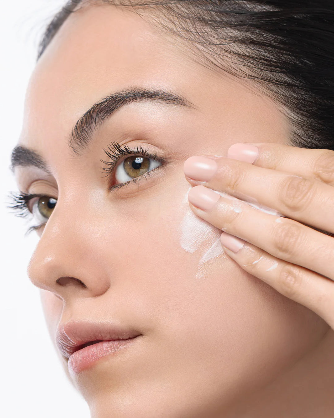 Close-up of a woman applying cream to her face