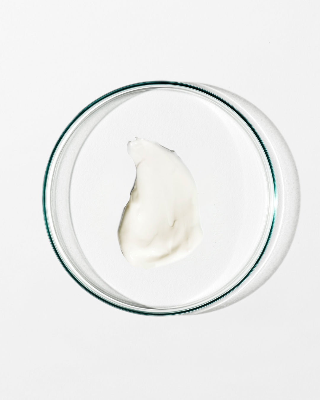 Glass bowl with a dollop of white cream on a white background