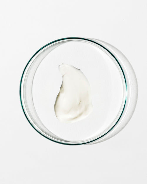 Glass bowl with a dollop of white cream on a white background