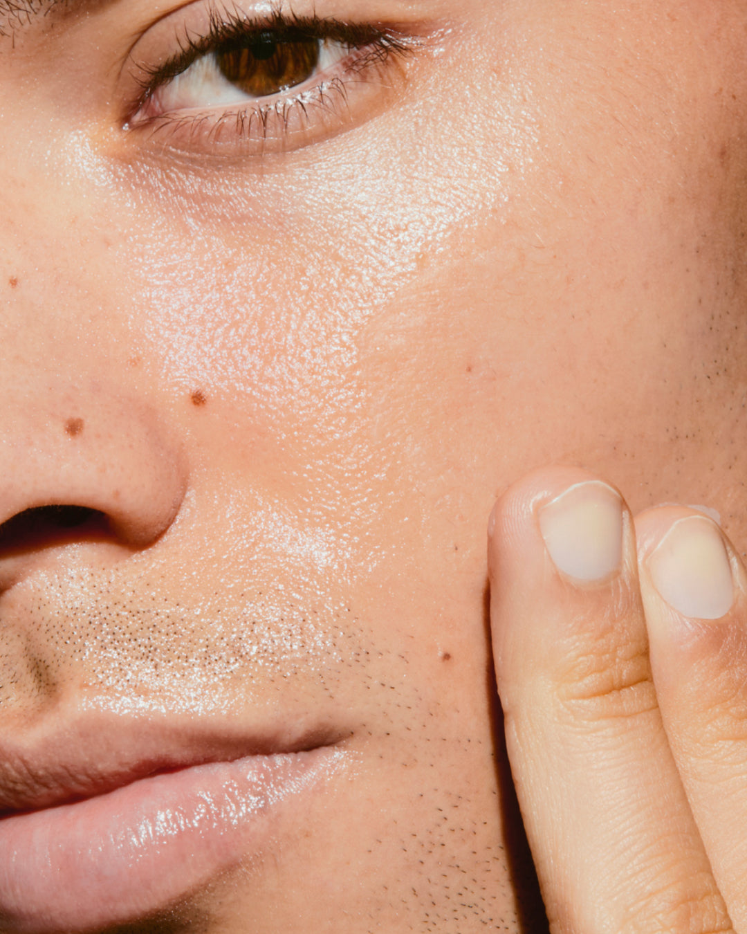 Close-up of a person's face with fingers pressed to the skin.