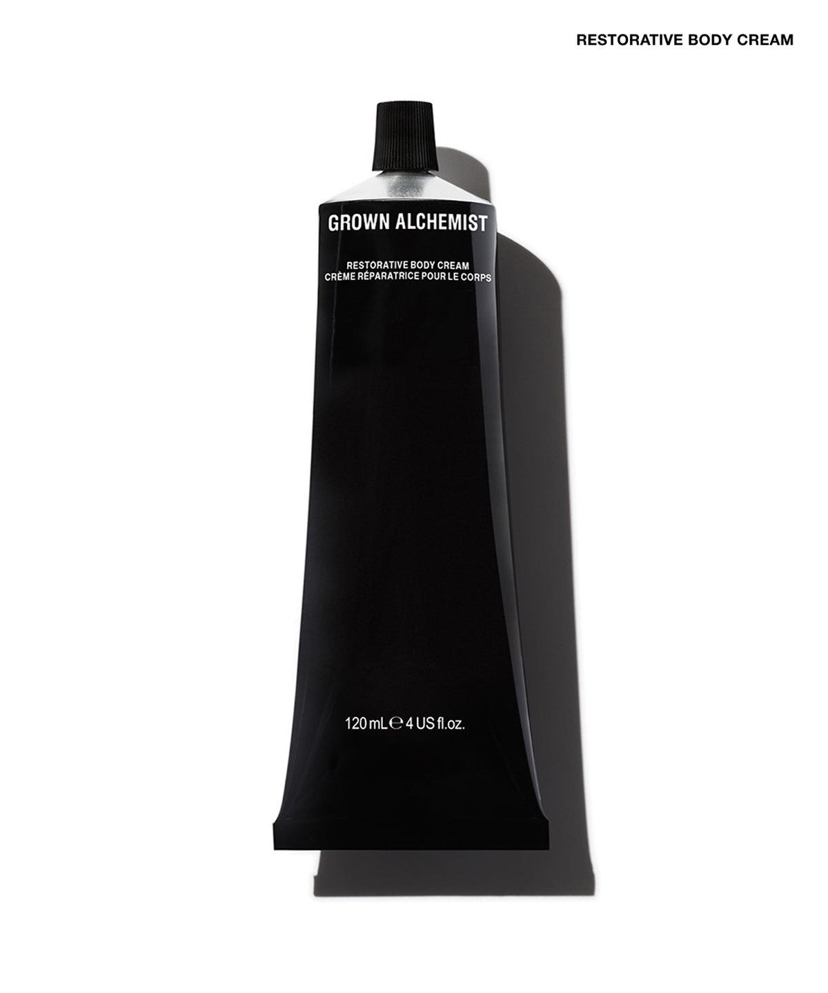 A black squeeze tube of Grown Alchemist Restorative Body Cream on a white background with a soft shadow.