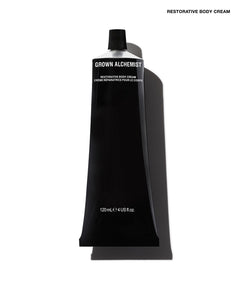 A black squeeze tube of Grown Alchemist Restorative Body Cream on a white background with a soft shadow.
