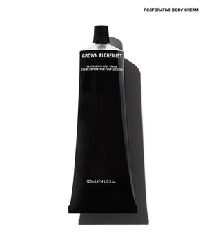 A black squeeze tube of Grown Alchemist Restorative Body Cream on a white background with a soft shadow.
