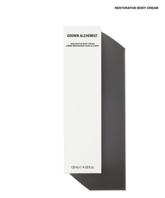 A tall, narrow white box for Grown Alchemist Restorative Body Cream, shown on a white background with a strong dark shadow to the right. The box has black text and is photographed from a top-down angle.