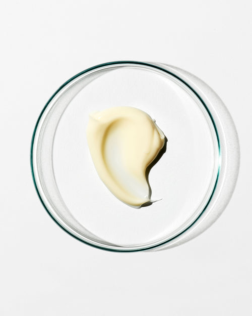 Glass bowl with a swirl of cream on a white background