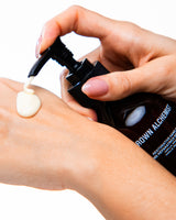 Person applying cream from a pump bottle labeled 'Grown Alchemists' on their wrist.