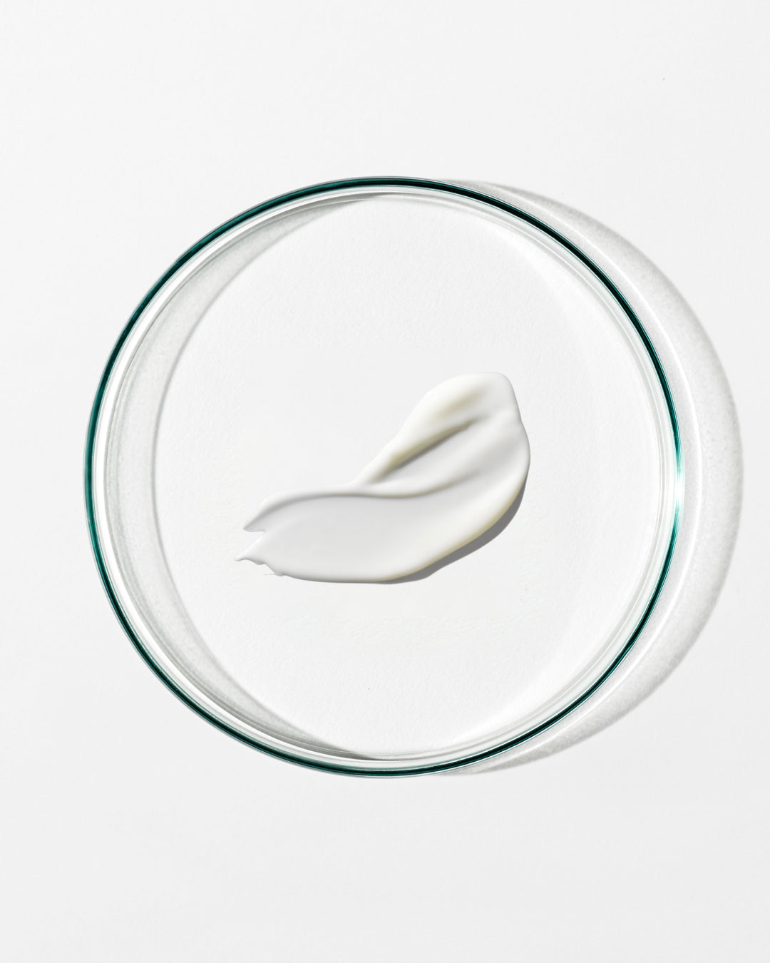 White cream on a clear glass lid against a white background