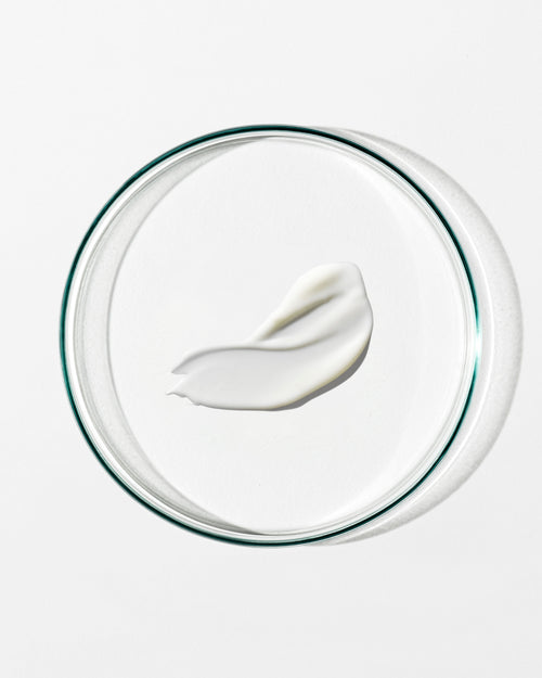 White cream on a clear glass lid against a white background