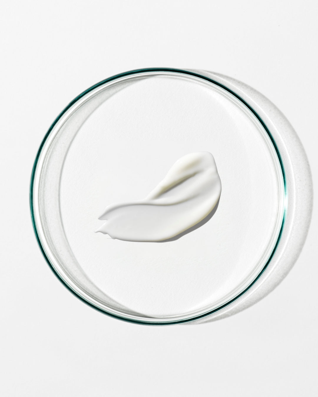 White cream on a clear glass plate with a white background