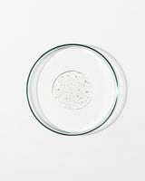 Clear glass pie dish with a dollop of liquid on a white background
