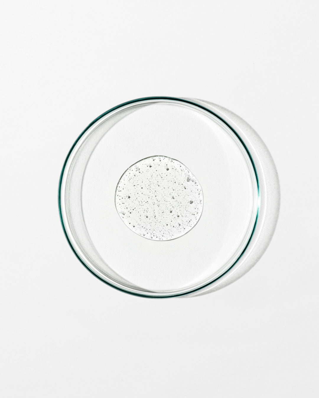 Clear glass pie dish with a dollop of liquid on a white background