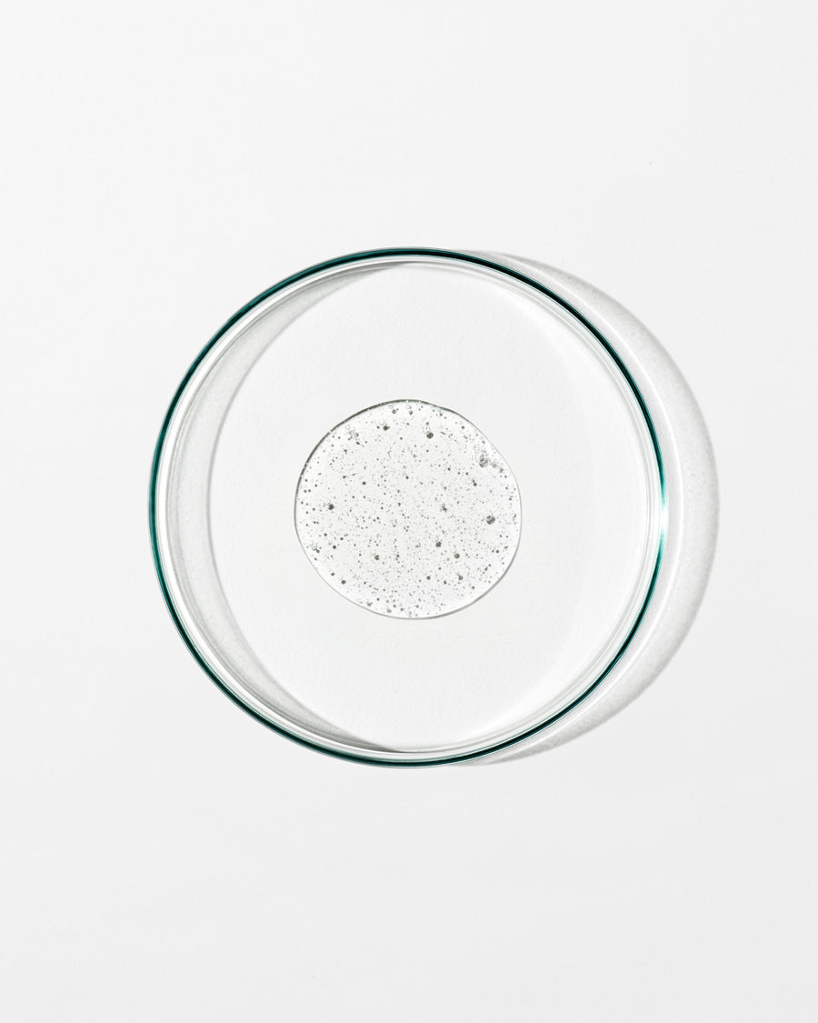 Clear glass pie dish with a dollop of liquid on a white background