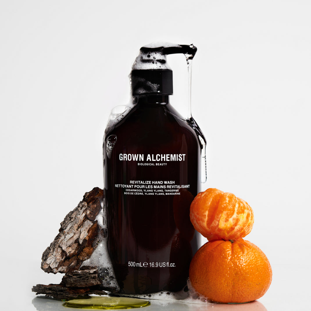 Bottle of Revitalize Hand Wash with oranges and a rock on a white background