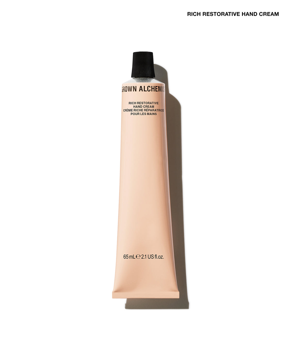 A squeeze tube of Grown Alchemist Rich Restorative Hand Cream in a pale peach-beige colour with a black cap, shown on a white background with a soft shadow.