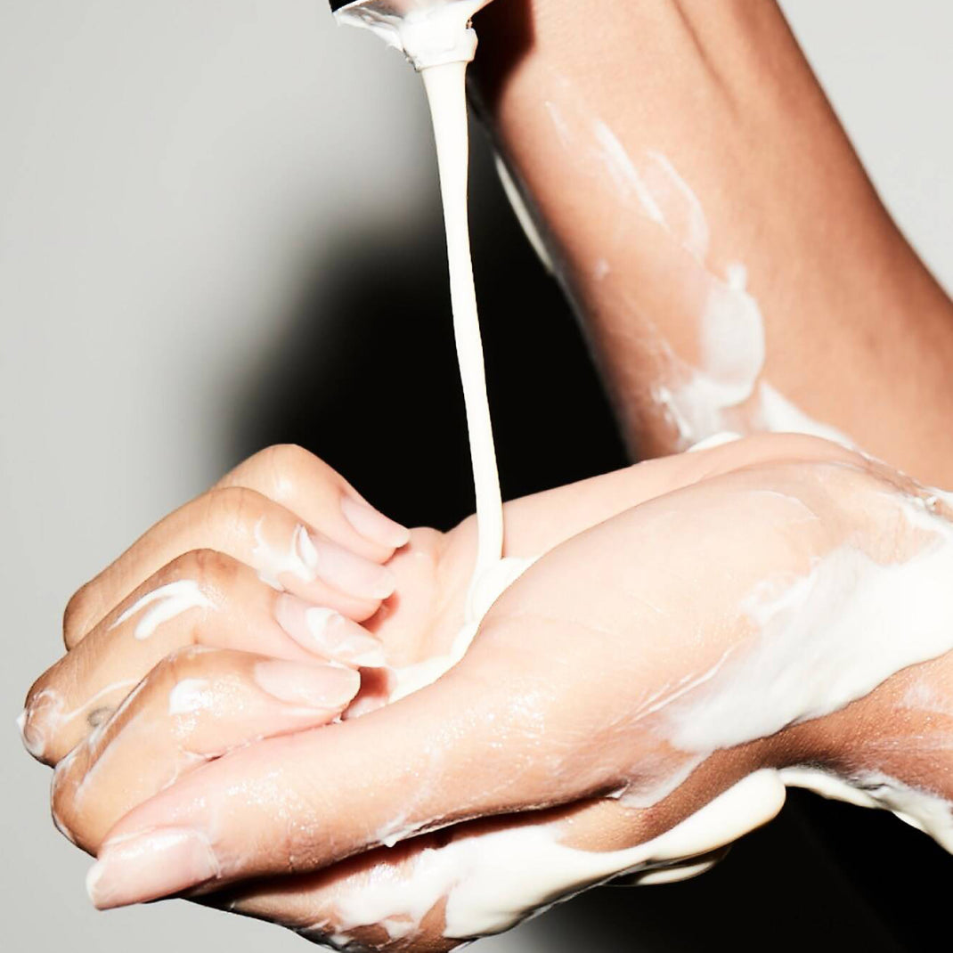 Hand applying Rich Restorative Hand Cream on another hand against a white background