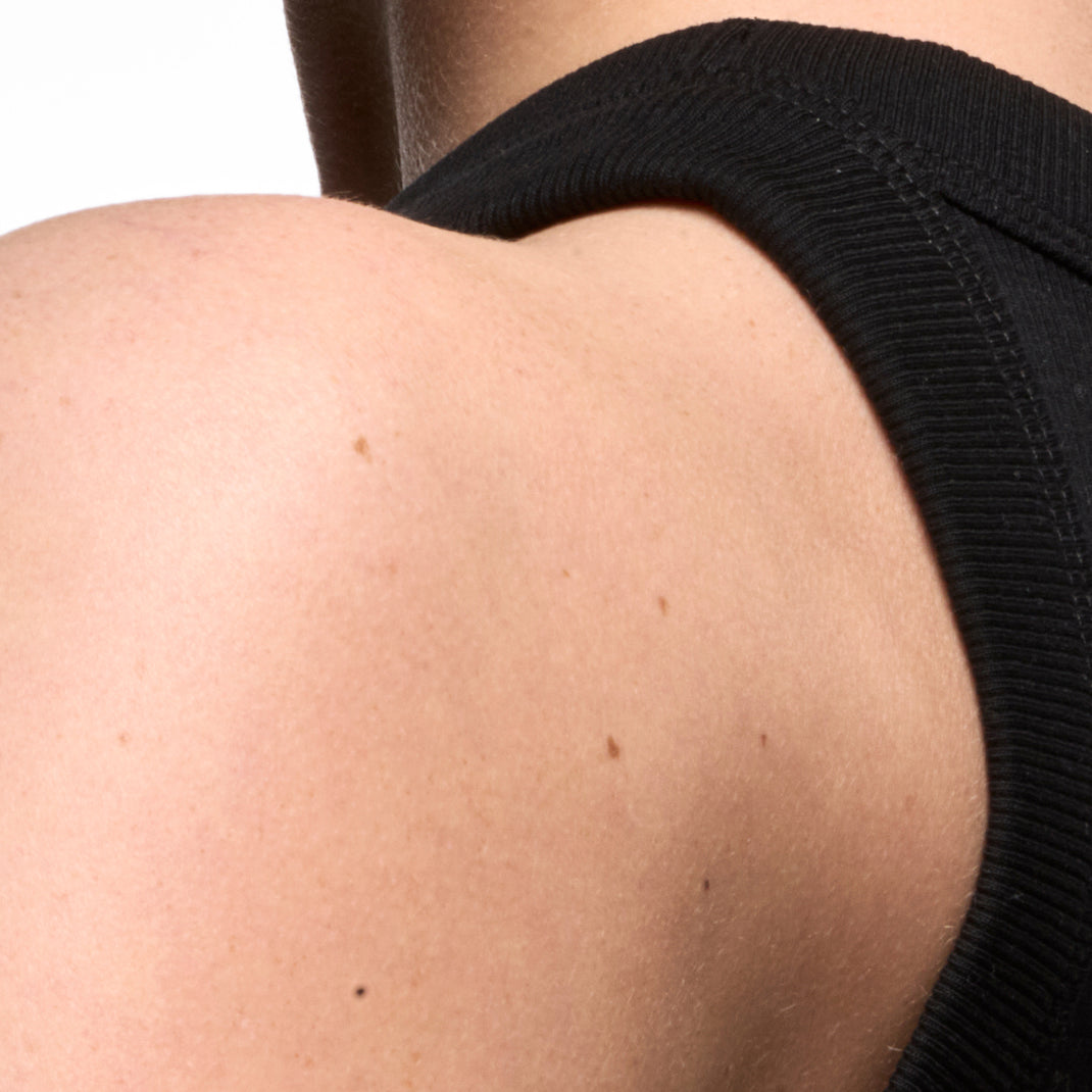 Close-up of a person wearing a black sleeveless top, showing shoulder and arm area.