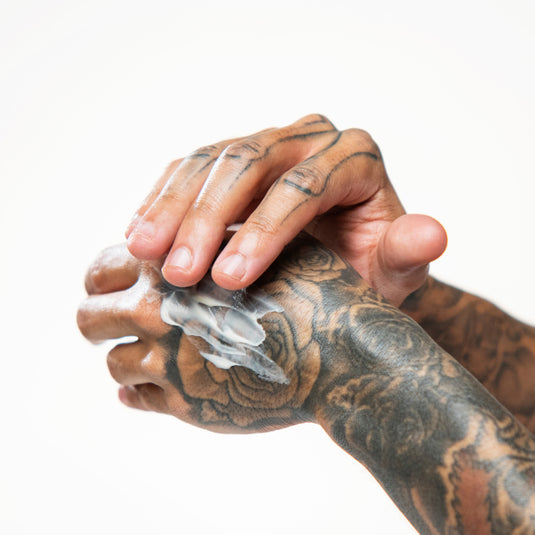 Hand applying Rich Restorative Hand Cream on another hand against a white background
