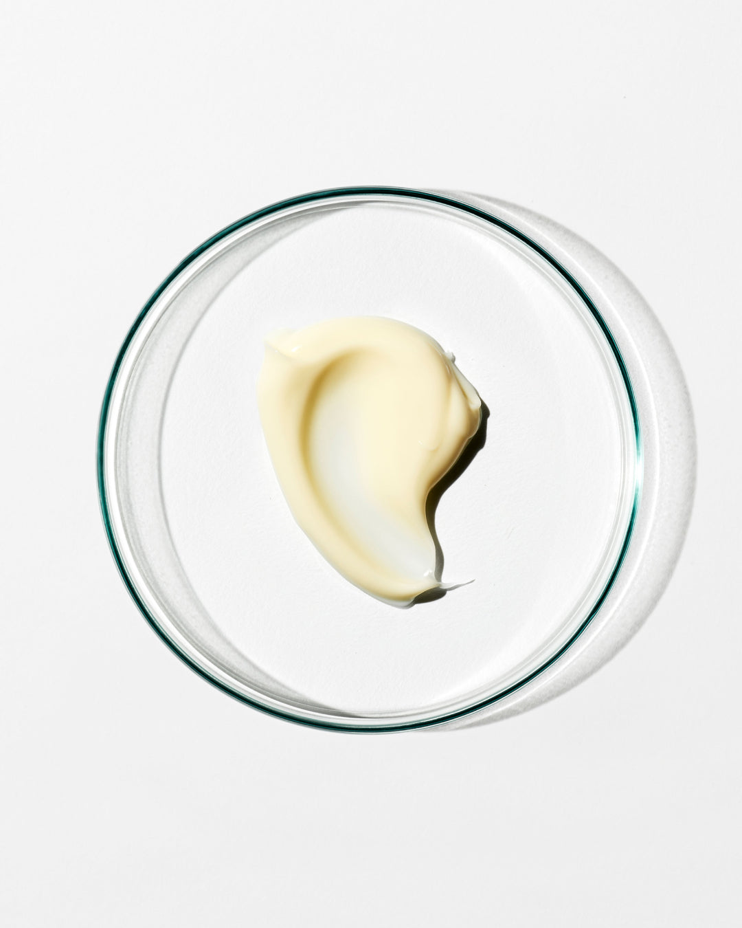 Glass bowl with a dollop of cream on a white background