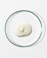 White dollop of cream in a clear glass container on a white background