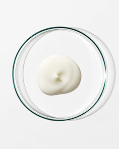 White dollop of cream in a clear glass container on a white background