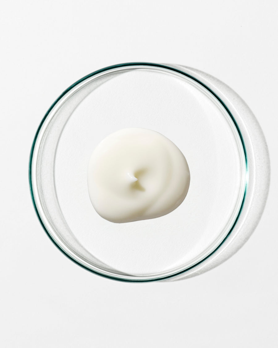 White dollop of cream in a clear glass container on a white background