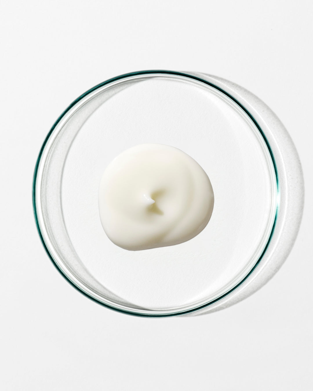 White cream in a clear glass container on a white background