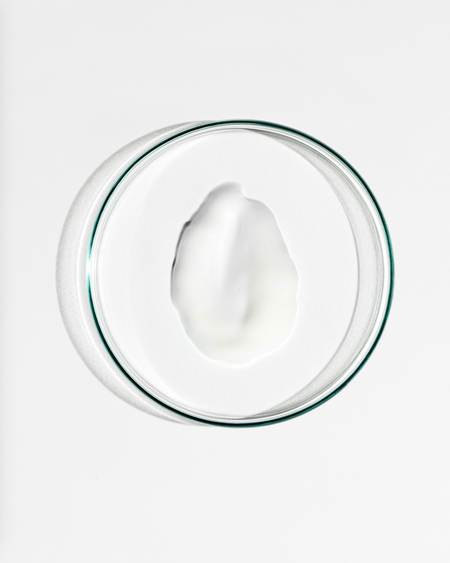 Glass bowl with a white cream on a white background