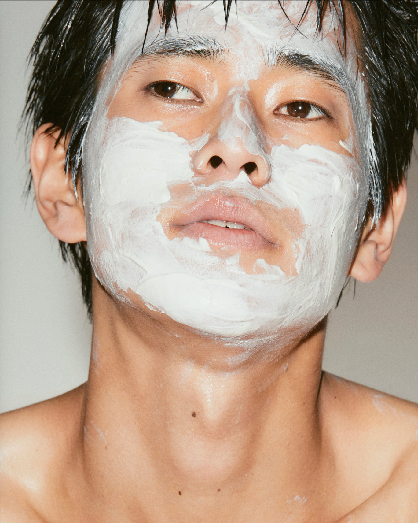 Person with a white facial mask on a plain background