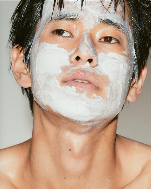 Person with a white facial mask on a plain background