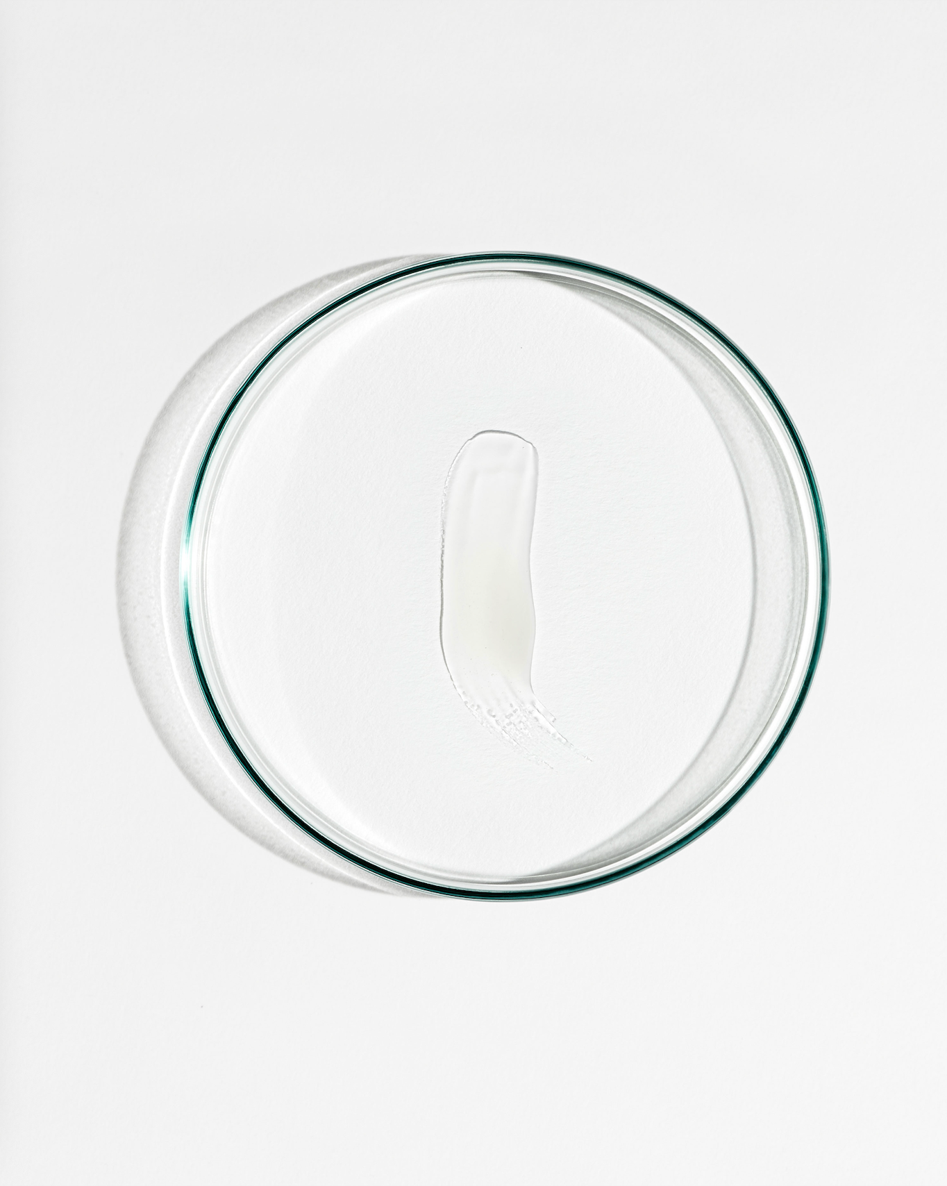 Clear glass lid with white cream on a white background