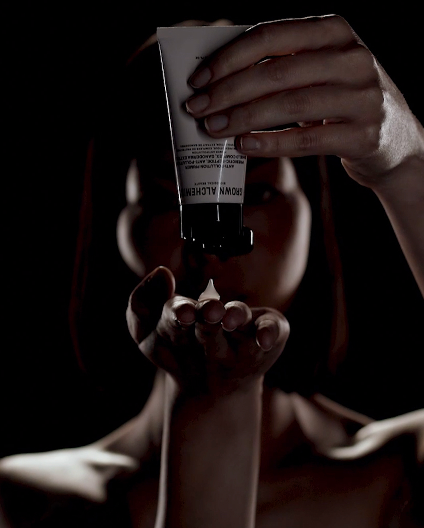 Person holding a tube of Grown Alchemist primer in a dark setting