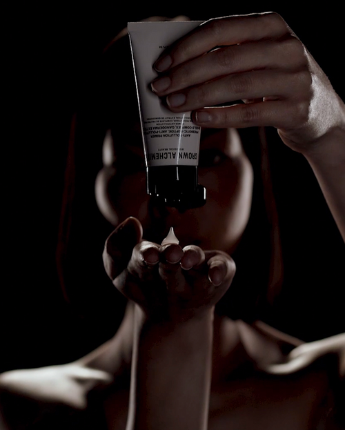 Person holding a tube of Grown Alchemist primer in a dark setting