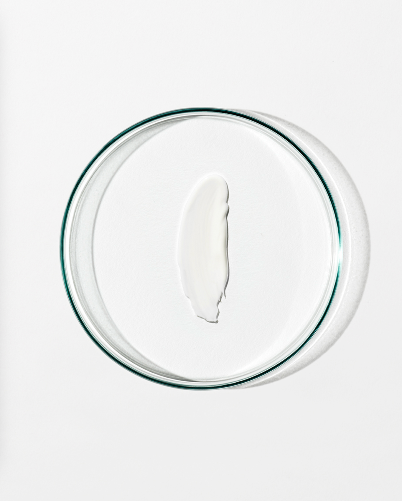 Clear dish with a dollop of white cream against a white background