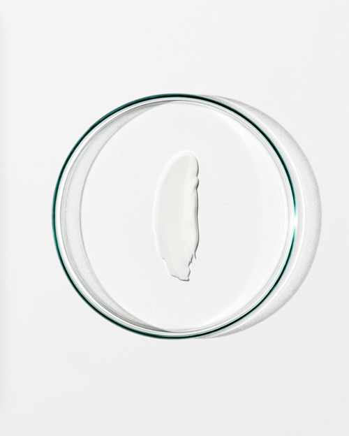 Clear dish with a dollop of white cream against a white background