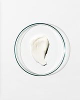 Glass bowl with swatch of moisturiser on a white background